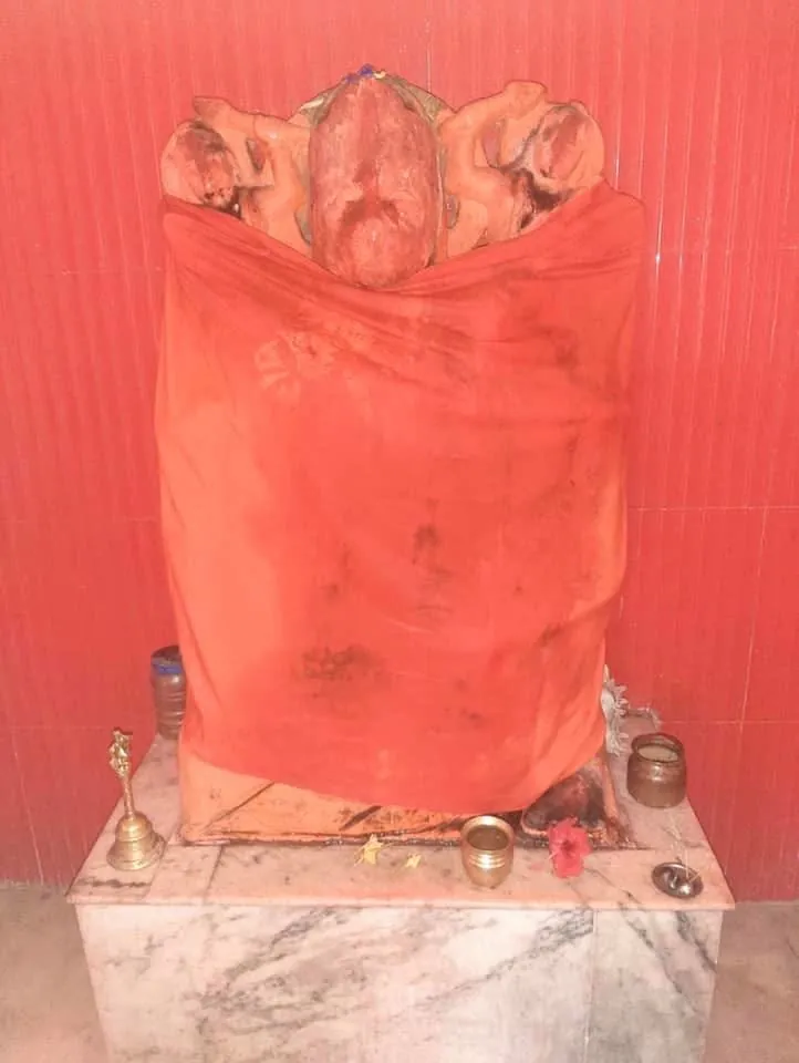 नारंगी वस्त्र में हनुमान जी का सिंदूर-लेपित विग्रह, संगमरमर की वेदी और पूजा-पात्र